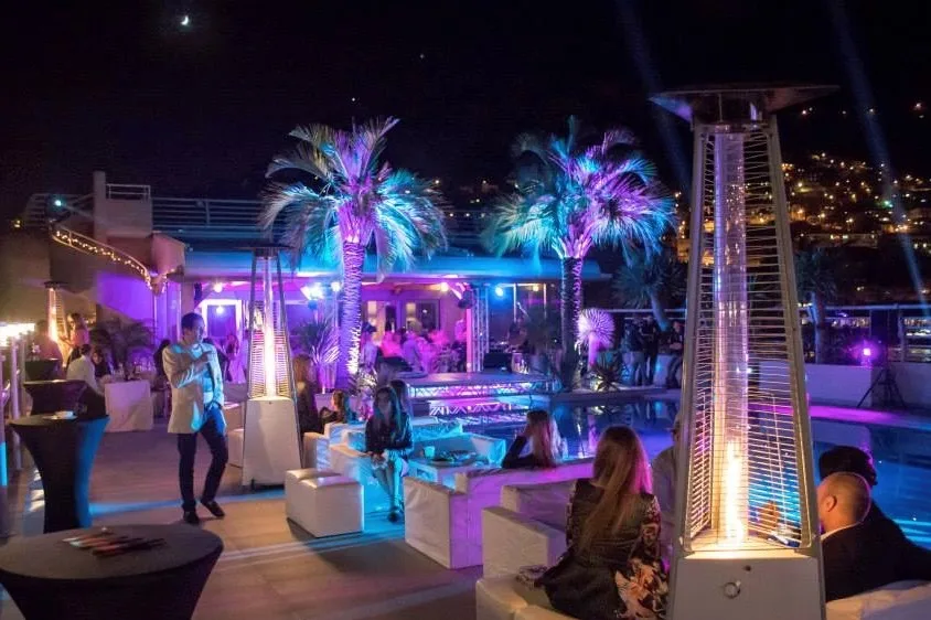 Lounge a bordo piscina con palme illuminate durante il party notturno