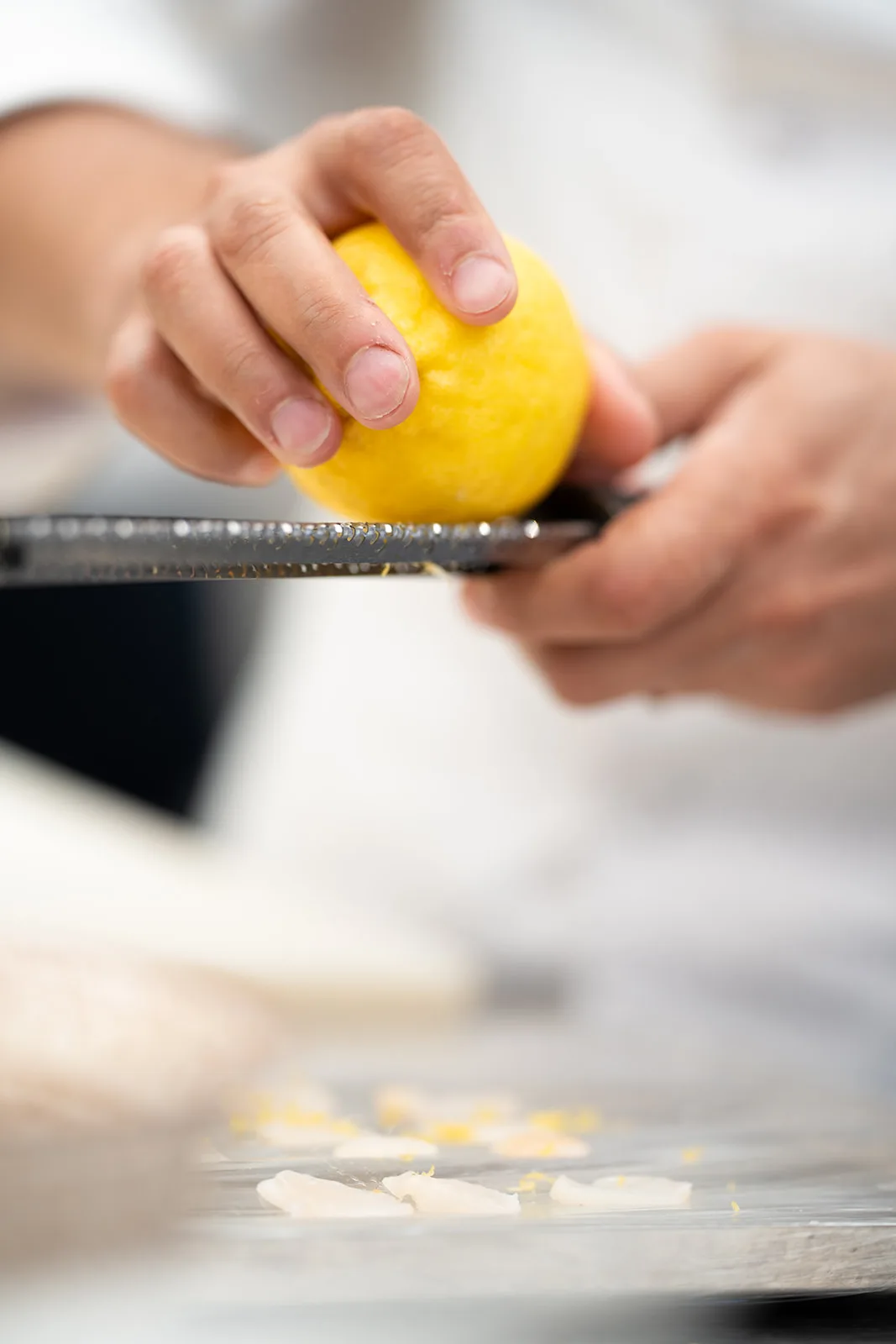 Lo chef gratta la scorza di limone fresco sul tagliere