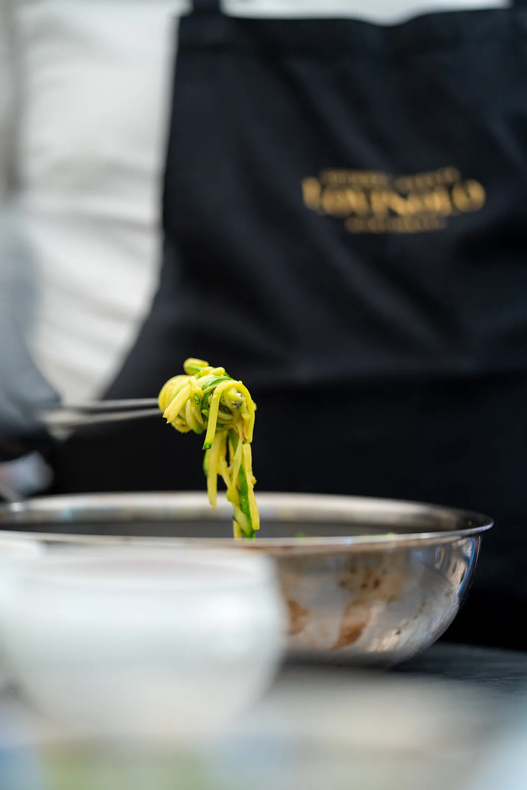 Zucchine julienne sollevate con la forchetta sopra la pentola