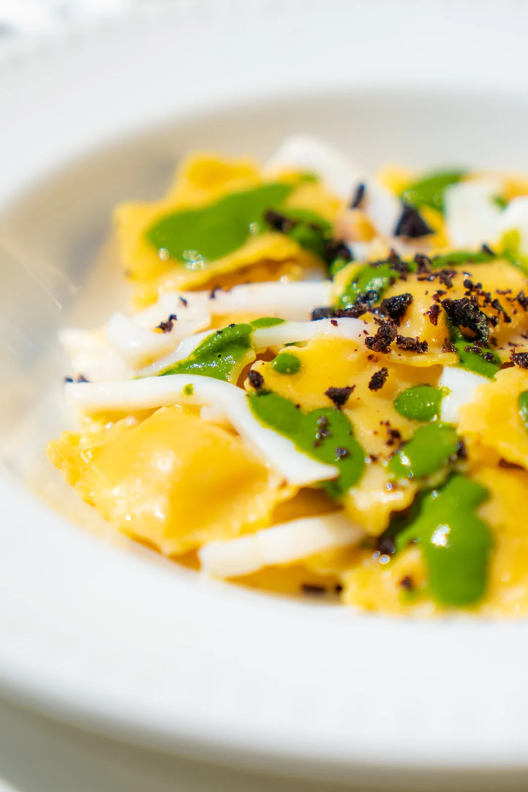 Ravioli al tartufo guarniti con salsa verde e lamelle bianche