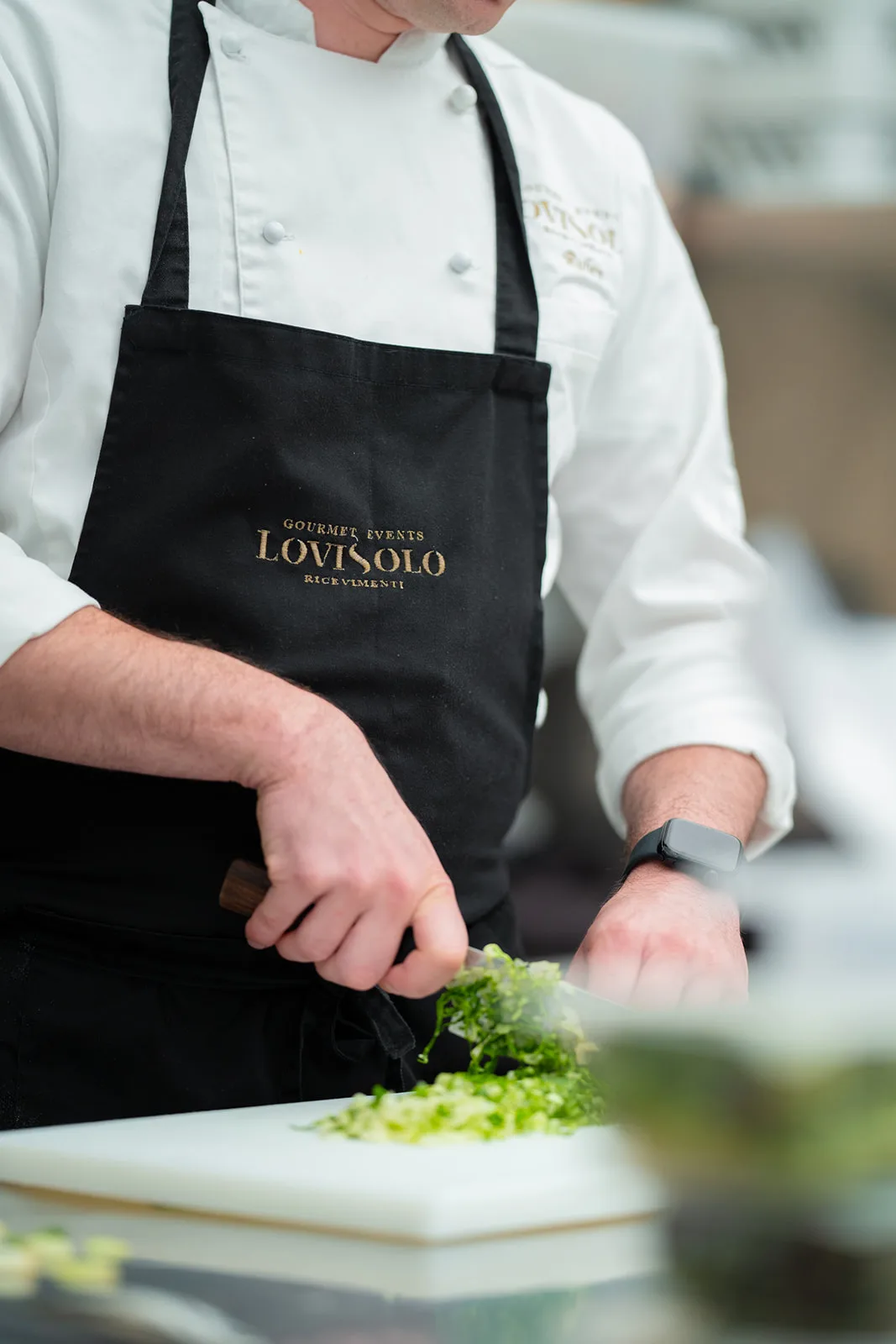 Chef con grembiule Lovisolo taglia erbe aromatiche sul tagliere