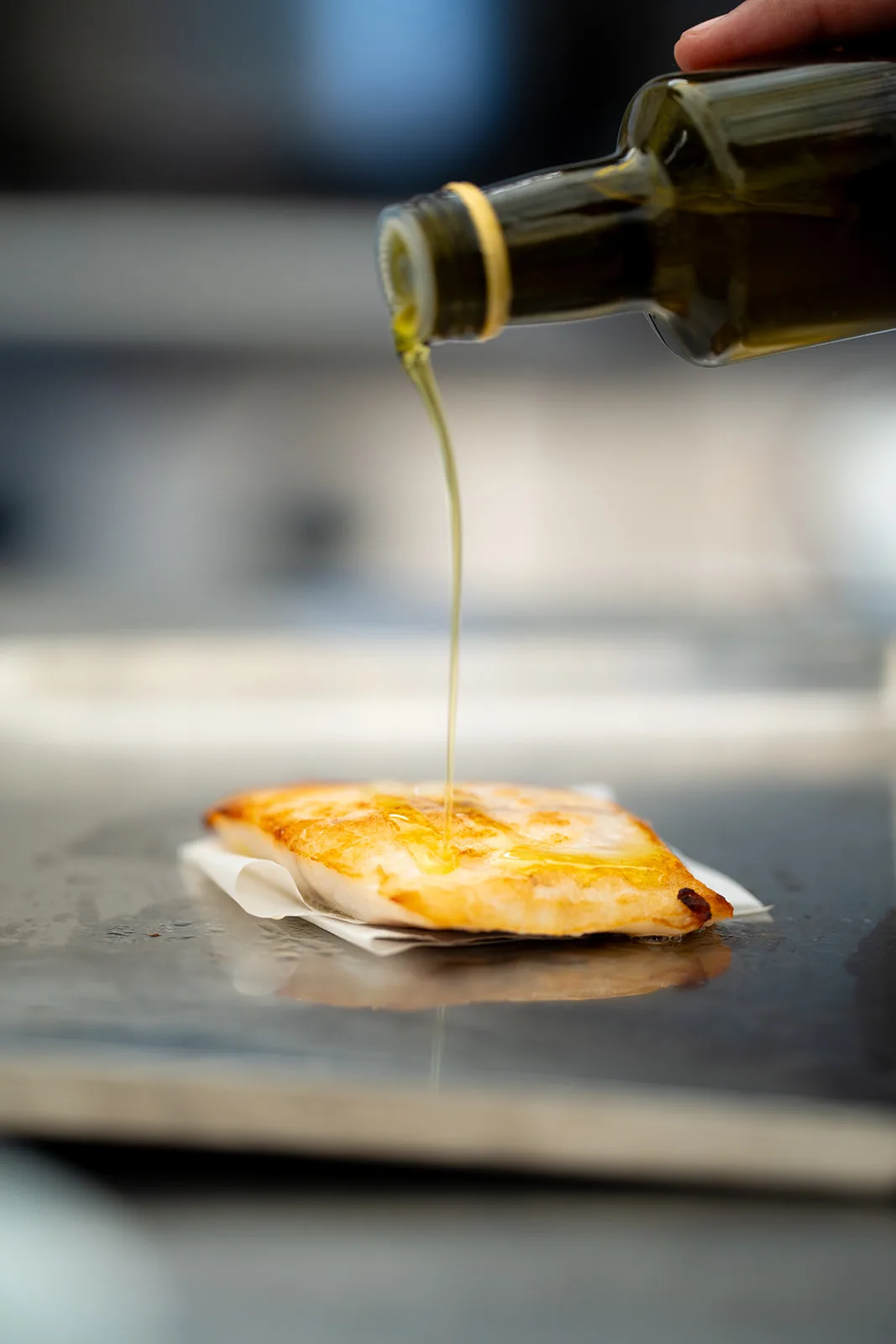 Filo d'olio versato lentamente su un filetto di pesce croccante
