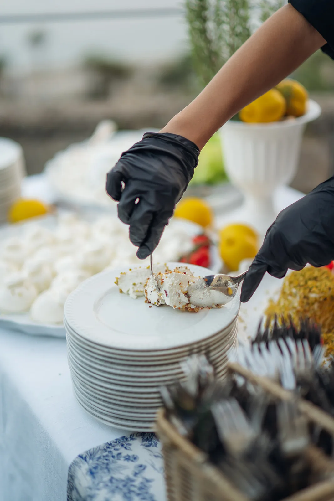 camerieri impiattano burrata con granella di pistacchio su torre di piatti