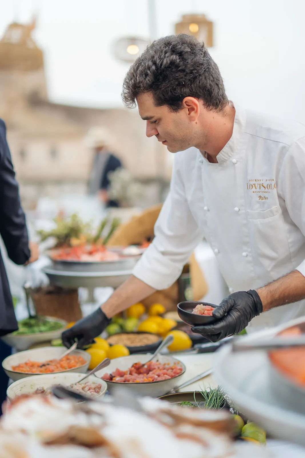 lo chef prepara piccoli assaggi di crudo tra limoni al banco del catering