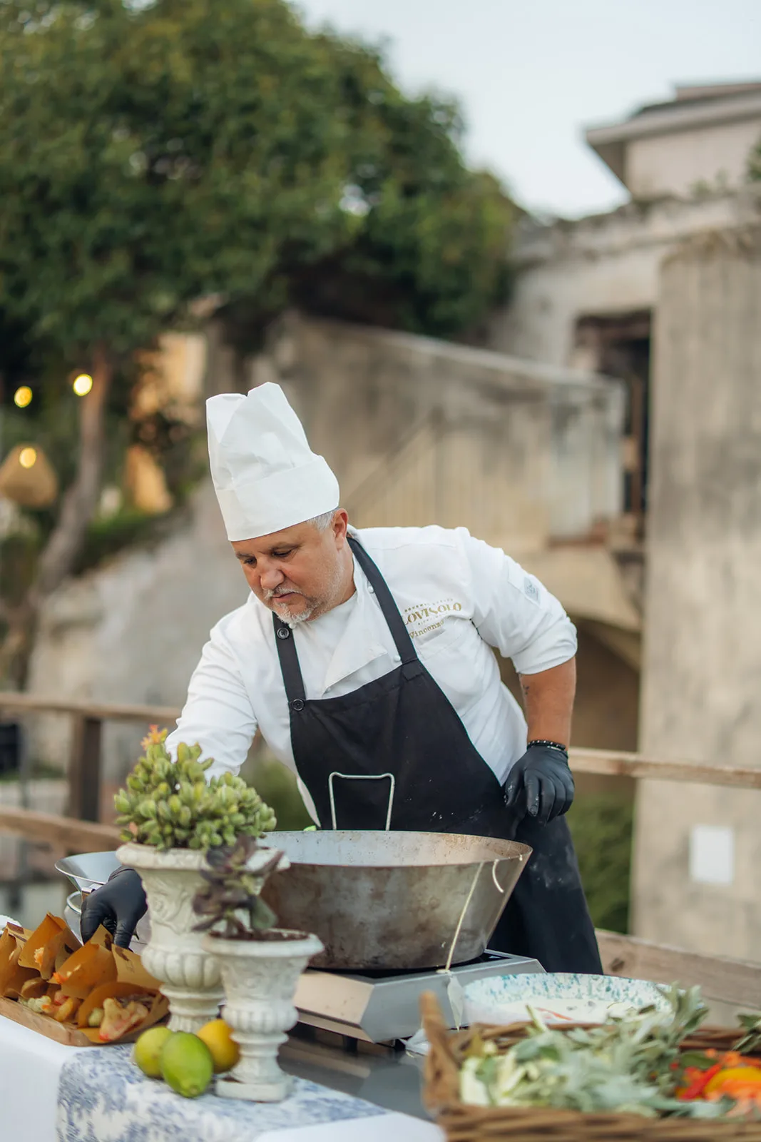 lo chef Lovisolo cucina all'aperto tra vasi e fornello da campo