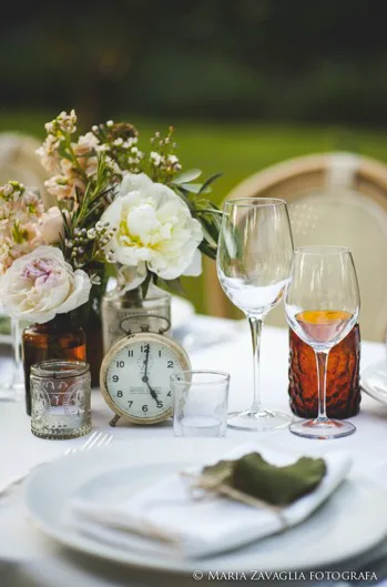 dettaglio della mise en place con fiori bianchi e orologio vintage