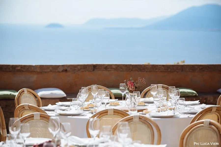 Tavolo in rattan apparecchiato su terrazza con vista sul mare