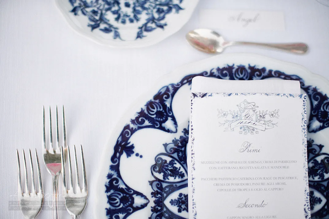 Menu e piatto decorato in blu e bianco su tovaglia candida