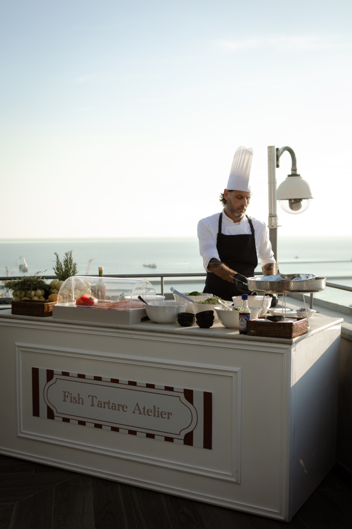 Lo chef compone piatti al Tartare Atelier con il mare sullo sfondo