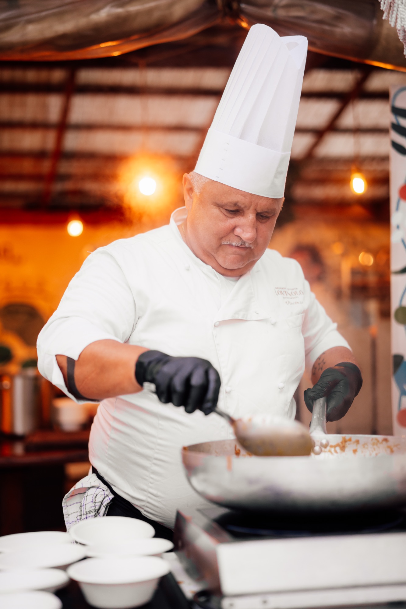 Le chef en toque blanche remue une sauce dans la poêle pendant le service