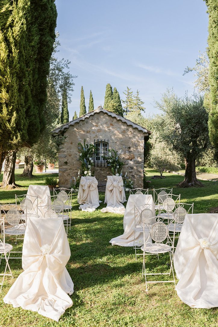 Allestimento cerimonia tra ulivi e cipressi davanti a un rustico in pietra provenzale