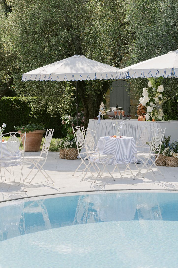 Angolo lounge a bordo piscina con ombrelloni bianchi e tavolino per l'aperitivo