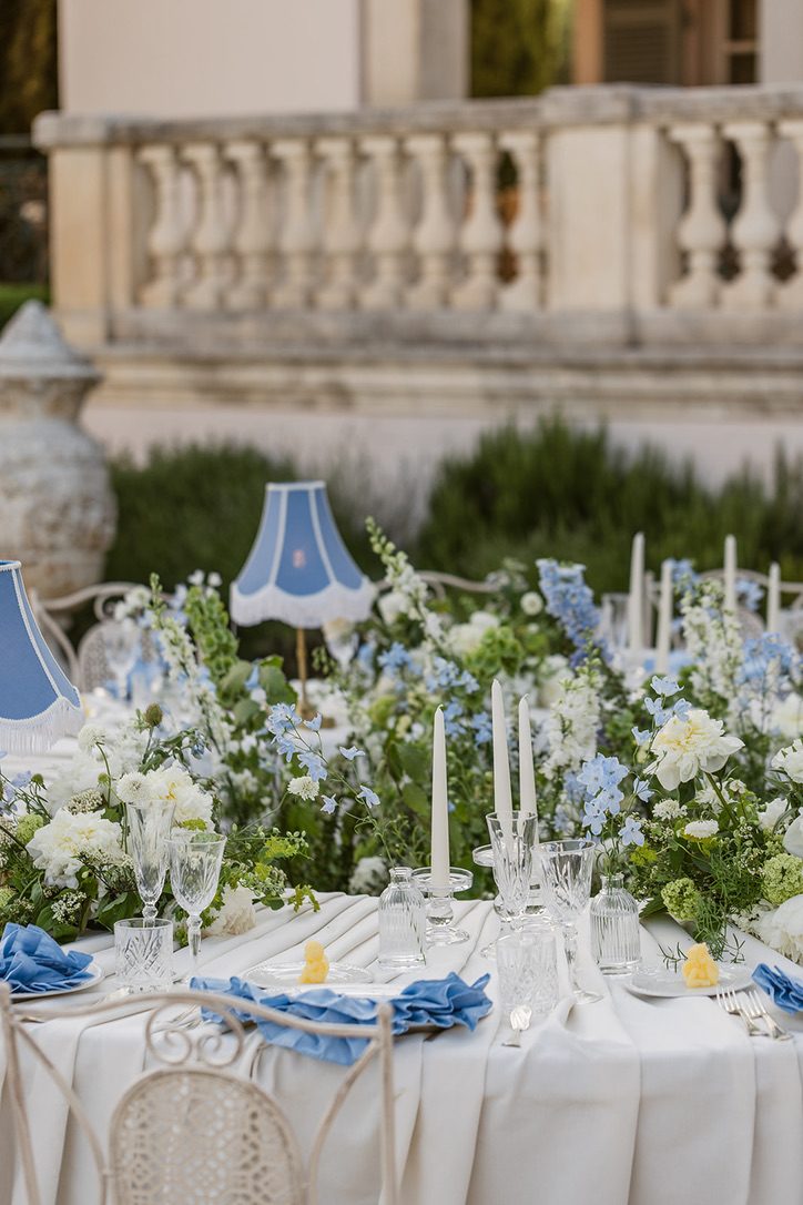 Dettaglio del tavolo con candele, fiori bianchi e azzurri e tovaglioli blu