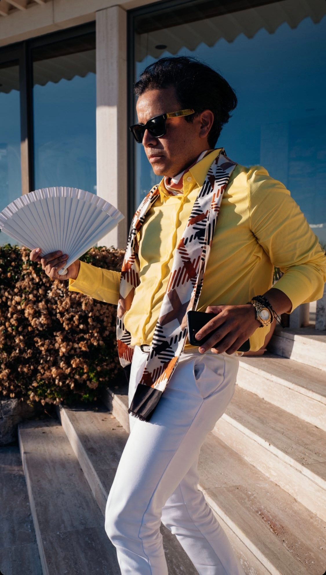 ospite in camicia gialla si rinfresca con un ventaglio sulla scalinata